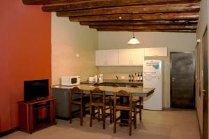 a kitchen with a table with chairs and a refrigerator at Cabañas Entre Hileras in Ciudad Lujan de Cuyo