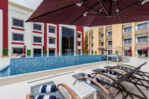 an outdoor pool with chairs and an umbrella at Best Western Plus Al Qurayyat City Center in Al Qurayyat