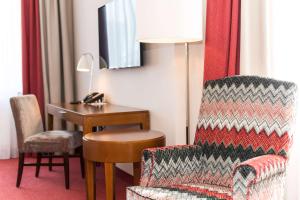 ein Hotelzimmer mit einem Schreibtisch, einem Stuhl und einem Tisch in der Unterkunft Best Western Plus Hotel St. Raphael in Hamburg