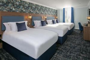 una fila de cuatro camas en una habitación de hotel en Best Western Hotel 99 en Blackburn