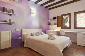 een slaapkamer met paarse muren en een bed met handdoeken erop bij Cana Daisy - Santa Eulalia del Rio in Santa Eularia des Riu