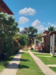 a walkway between two houses with palm trees at Vila Vintém Chalés in Praia de Moitas