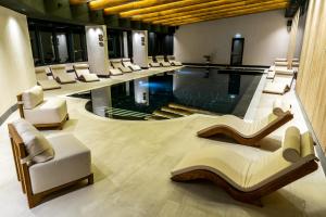 a hotel lobby with a pool and lounge chairs at Hotel Roman Maramures - Ski & Spa Resort in Statiunea Borsa +83 photos