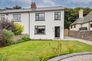 a white house with a garden in front of it at The Bank House- Luxury 3 bed cottage with hot tub! in Silverdale