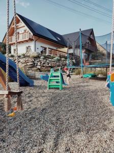um parque infantil em frente a uma casa com baloiços em Domek pod Szarowym lasem em Wisla