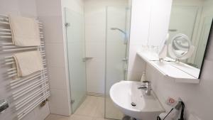 Baño blanco con lavabo y espejo en Gästehaus Wissler, en Todtnau