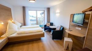 a hotel room with a bed and a flat screen tv at Gästehaus Wissler in Todtnau