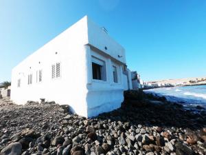 a white building on the rocks next to the ocean at La casa de la playa in Las Palmas de Gran Canaria