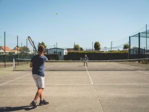 duas pessoas a jogar ténis num campo de ténis em Camping Les Garennes em Rang-du-Fliers