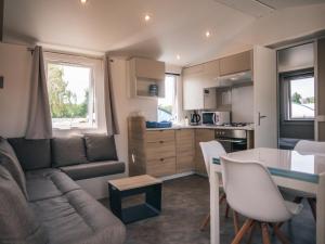 uma cozinha e sala de estar com um sofá e uma mesa em Camping Les Garennes em Rang-du-Fliers