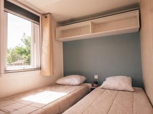 2 camas en una habitación con ventana en Camping Les Garennes, en Rang-du-Fliers