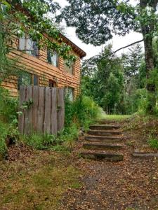 una casa con una valla de madera y escaleras delante en Paisaje Nativo en Villa La Angostura