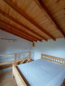 Cama en habitación con techo de madera en Paisaje Nativo en Villa La Angostura