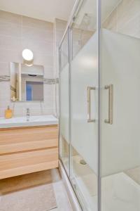 y baño con ducha acristalada y lavamanos. en Logement Sarah en Evry-Courcouronnes