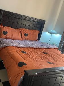 a bed with an orange comforter and pillows at Kim luxury apartment in Kampala