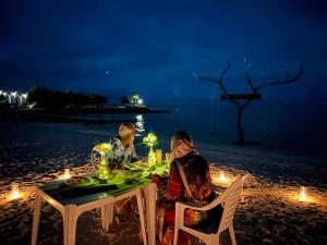 two people sitting at a table on the beach at night at Burulu Inn in Gaafaru