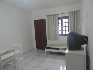 uma sala de estar com uma televisão e uma janela em Pousada Camacho em Jaguaruna