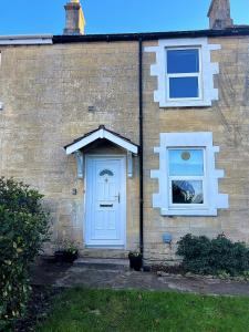 a house with a blue door and two windows at Rush Hill Cottage - with parking for 2 cars in Bath