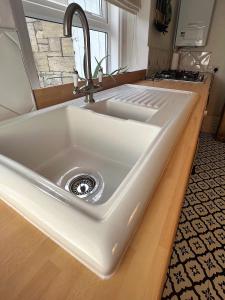 a white kitchen sink with a faucet on a counter at Rush Hill Cottage - with parking for 2 cars in Bath