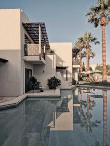a house with a swimming pool and palm trees at Cretan Malia Park a Member of Design Hotels in Malia