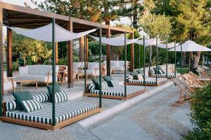 - un ensemble de chaises et de parasols sur une terrasse dans l'établissement Cretan Malia Park a Member of Design Hotels, à Mália