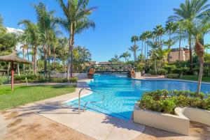 een zwembad in een resort met palmbomen bij Duplex Penthouse in Rio Real Golf, Marbella in Marbella