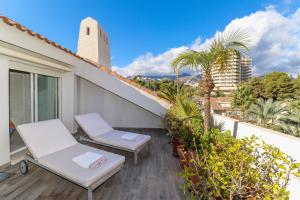 een balkon met 2 stoelen en palmbomen en een gebouw bij Duplex Penthouse in Rio Real Golf, Marbella in Marbella