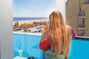 Una donna che guarda fuori da una finestra sulla spiaggia di Hotel Spiaggia Marconi a Rimini