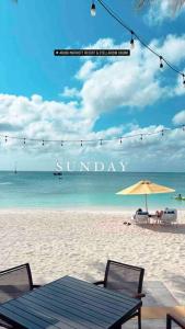 Savaneta的住宿－Beautiful house in Sabana Basora Aruba!，海滩上,有桌子和遮阳伞,日光时还有文字