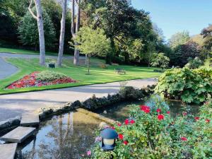 einen Garten mit einem Teich, Blumen und einem Park in der Unterkunft Palmerston House with Sea and Downs Views in Ventnor