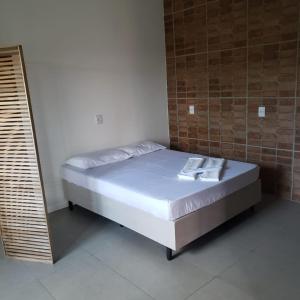 ein Bett in einem Zimmer neben einer Ziegelwand in der Unterkunft Morada Flores de Alaíde - Pinheira in Pinheira