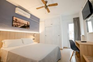 a bedroom with a white bed and a ceiling fan at Eurohotel in Mahón