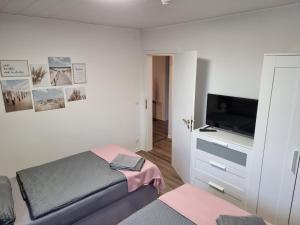 a white bedroom with a bed and a television at Gästehaus-Ferienwohnung-Appartement mit Terrasse - Nähe Kliniken/ Herzzentrum in Bad Oeynhausen