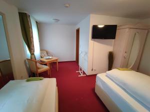 um quarto com duas camas e uma mesa e uma televisão em Room in BB - Pension Forelle - double room em Forbach