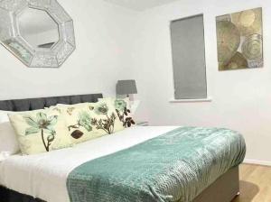 una camera da letto con un letto con una coperta verde e uno specchio di Skyline Views - Spacious Flat near Cutty Sark & Greenwich with parking a Londra