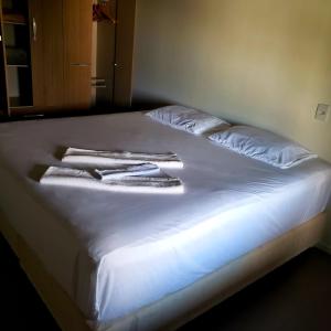 ein Bett mit weißer Bettwäsche und weißen Handtüchern darauf in der Unterkunft Morada Flores de Alaíde - Pinheira in Pinheira