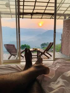 un hombre tendido en una cama mirando a la puesta de sol en Brisk Ella Retreat en Ella