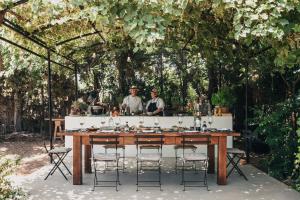 two men standing behind a wooden table with chairs at Cretan Malia Park a Member of Design Hotels in Malia