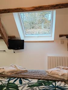 - une chambre avec un lit, une fenêtre et une télévision dans l'établissement A la Mémoire de Merlin & SPA, à Saint-Malon-sur-Mel