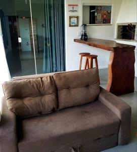 a brown couch in a living room with a bar at Morada Flores de Alaíde - Pinheira in Pinheira