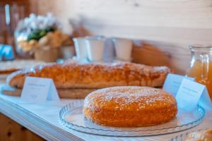 um bolo num prato numa mesa com outros produtos de pastelaria em Garnì Vecchio Comune em Flavon