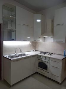 a white kitchen with a sink and a stove at Family hotel leni in Kvareli