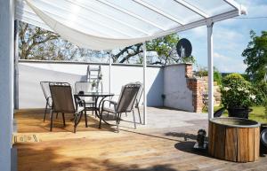 un patio con una mesa y sillas bajo un dosel blanco en Petite Maison, en Püttlingen