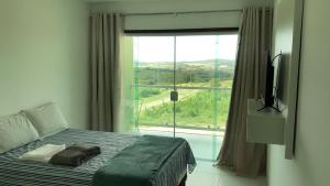 um quarto com uma cama e uma grande janela em FLAT VILLA MONTE CASTELO em Bezerros