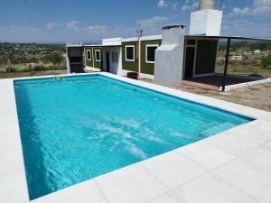 una gran piscina azul frente a una casa en Cabaña Buenos Recuerdos II en Villa Santa Cruz del Lago