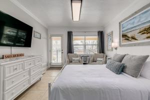 a white bedroom with a large bed and a tv at Enjoy the Pool while being Steps from Beach and Restaurants! - Coconut Villa's Suite 6 in St. Pete Beach