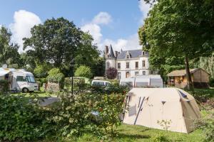 a tent in the grass in front of a house at Camping Domaine de la Ville Huchet in Saint Malo