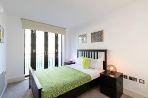 a bedroom with a bed with a green bedspread at City Apartments in London