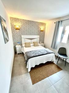a bedroom with a large bed and a chair at Luxury Beach Apartments Diama in Playa Honda