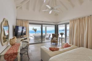una sala de estar con sofá y TV y el océano en 5 BR Luxurious Beachfront Villa with utmost privacy, en Les Terres Basses